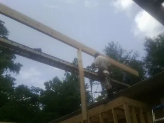 Carpenter setting a ridge beam over a new addition frame — Ice Dam Removal by Roofing Brothers in Anza