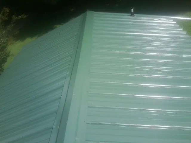 New green metal panels meeting at the ridge of a roof — Flat Roof Repair work by our crew in Anza