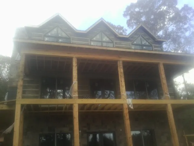 Dormers and porch framing on a large log home under construction — Roof Coating work by our crew in Anza