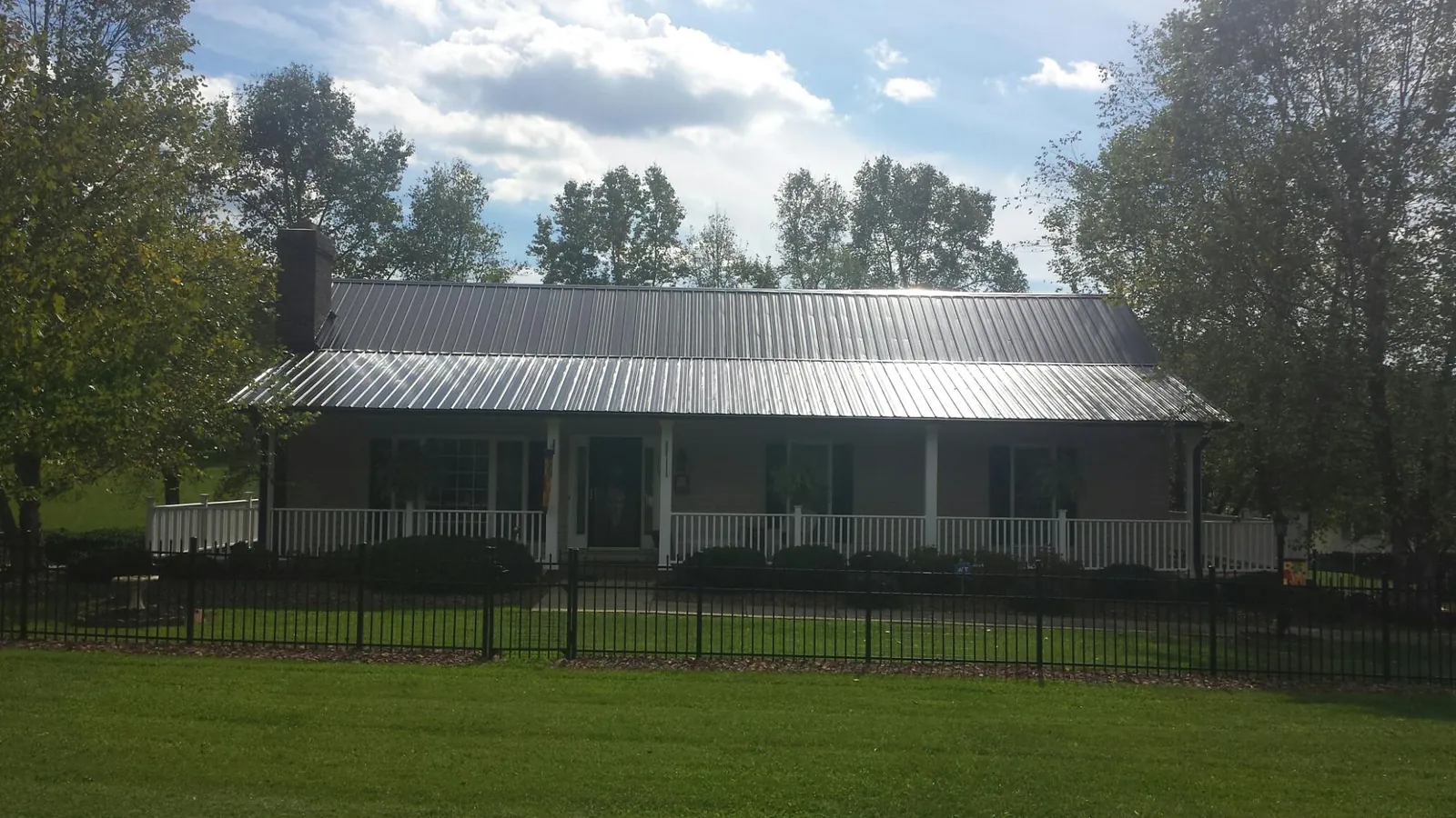 Gray metal roof on a brick ranch with a full width front porch — Gutter Guard Installation work by our crew in Anza