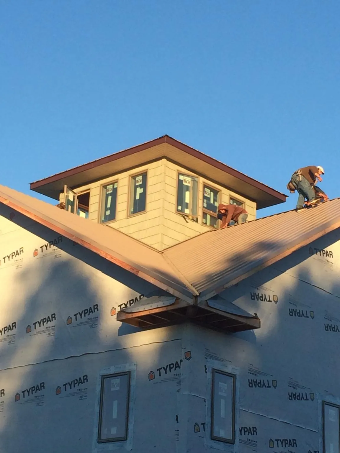 Roofers working around a rooftop cupola on a new metal roof at sunset — Roof Waterproofing in Anza by Roofing Brothers